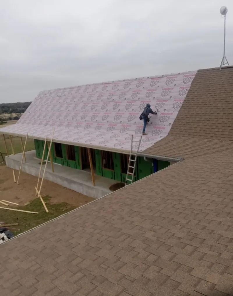 Worker preparing underlayment for a metal roof installation in Dalhart